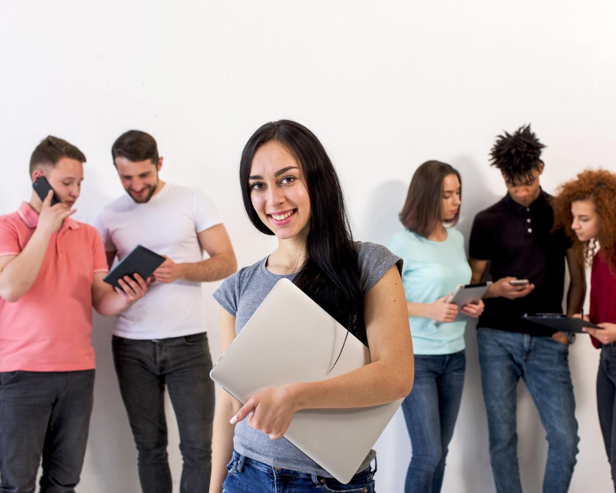 beautiful-happy-young-woman-looking-camera-holding-laptop-while-her-friends-busy-using-electronic-gadgets (1).jpg